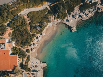 Vue aérienne d'une petite baie avec de l'eau claire, des bâtiments et des arbres adjacents.
