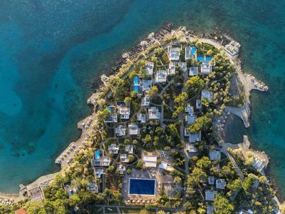 Vue aérienne d'une station côtière avec plusieurs bâtiments et une piscine près de la mer.