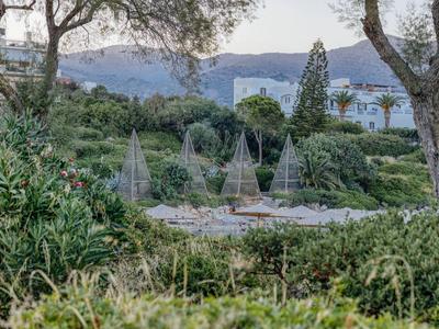 Jardin verdoyant avec parasols enroulés et arbres devant des montagnes et le ciel.