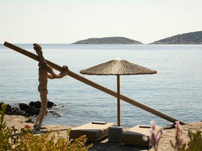 Plage tranquille avec chaises longues, parasol en paille et mer en arrière-plan.