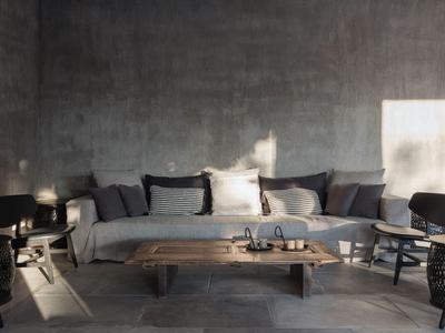 Soggiorno luminoso con divano grigio, tavolo di legno e sedie davanti a una parete grigia grezza