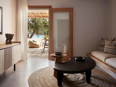 Salon élégant avec canapé, table basse ronde, tapis et accès à une terrasse extérieure.