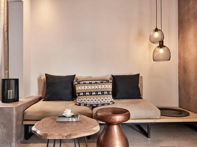 Salon moderne avec canapé beige, coussins décoratifs et tables basses en bois et métal.