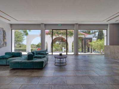 Hall d'hôtel moderne avec grandes fenêtres, canapé vert et œuvres d'art aux murs.