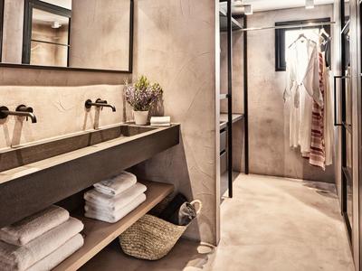 Salle de bain moderne avec double lavabo, serviettes et zone de douche aux tons neutres.