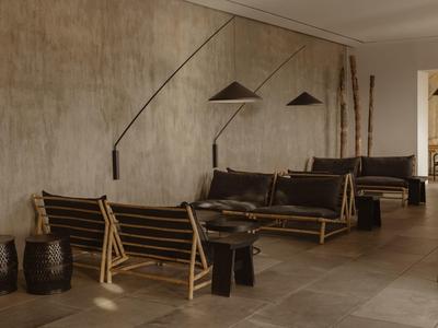 Espace d'attente moderne avec meubles en bambou et grandes lampes murales.