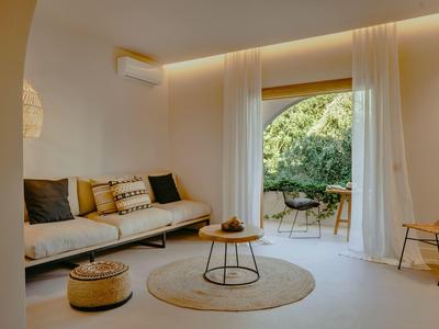 Salon lumineux avec canapé confortable, tapis rond et accès à un jardin