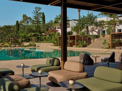 Espace extérieur moderne avec mobilier rembourré à côté d'une piscine calme dans un jardin d'hôtel.