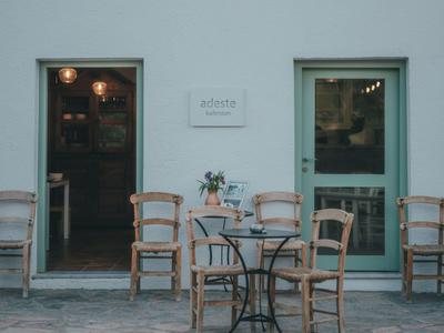 Espace extérieur d'un hôtel avec des chaises en bois, une table et une porte avec fenêtre en verre.