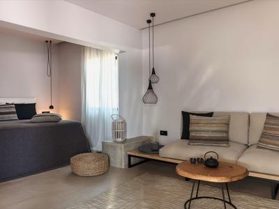 Chambre d'hôtel moderne avec lit sombre, canapé clair et décoration minimaliste.