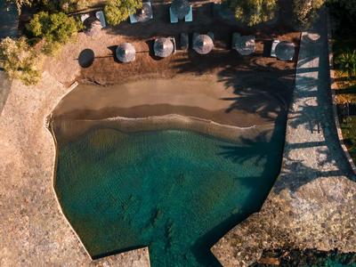 Vue aérienne d'une petite plage avec une eau turquoise claire et des places de stationnement à proximité.