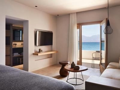 Chambre d'hôtel lumineuse avec vue sur la mer, terrasse, TV, lits et design moderne.