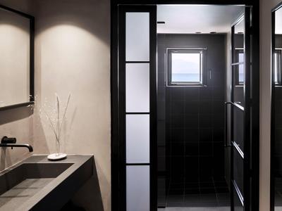 Salle de bain moderne avec cabine de douche noire et lavabo minimaliste.