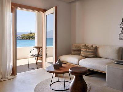 Chambre d'hôtel lumineuse avec terrasse, vue sur la piscine et la mer dans un cadre paisible.