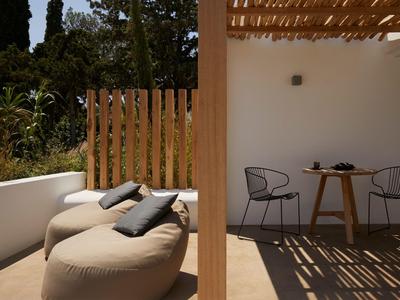 Terrasse avec des poufs rembourrés et une table avec des chaises dans un cadre ensoleillé.