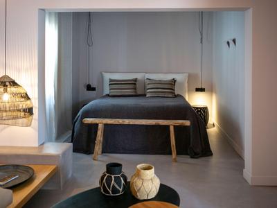 Chambre moderne avec banc en bois, literie sombre et éclairage doux.