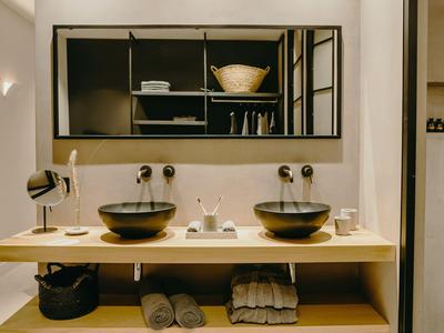 Aménagement de salle de bain moderne avec étagère en bois, deux lavabos noirs et grand miroir.