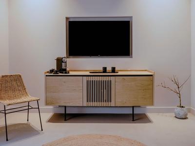 Espace moderne de chambre d'hôtel avec buffet, télévision, chaise et plante en pot dans un style minimaliste.