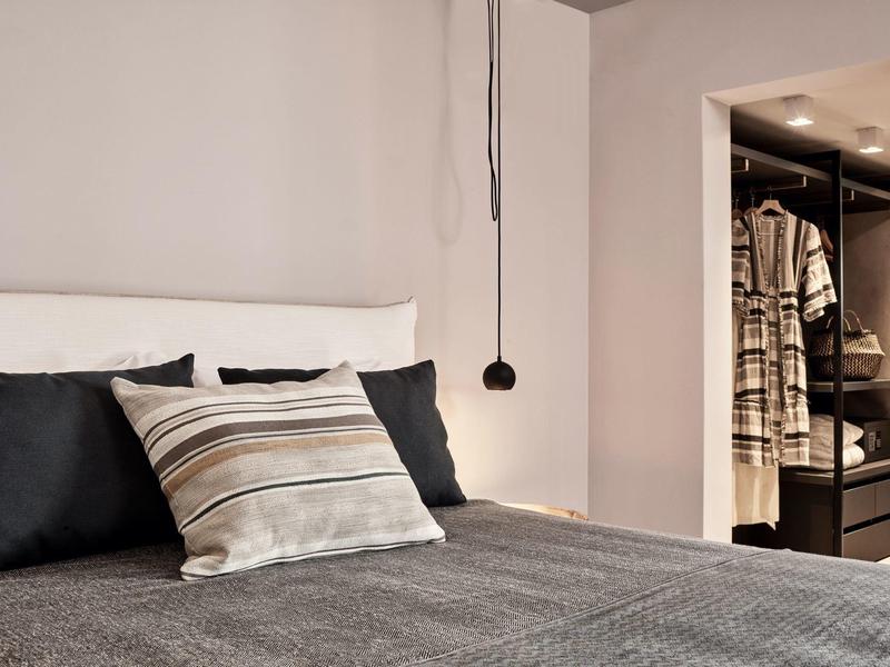 Chambre moderne avec lit confortable et dressing ouvert.