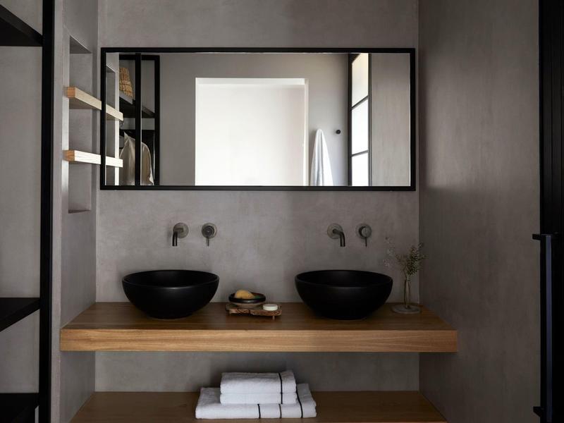 Salle de bain moderne avec deux vasques noires et grand miroir sur mur gris.