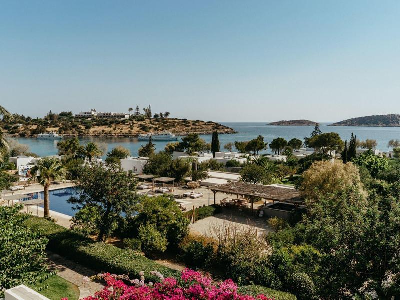 Vue sur un paysage côtier avec piscine, palmiers et ciel bleu clair.