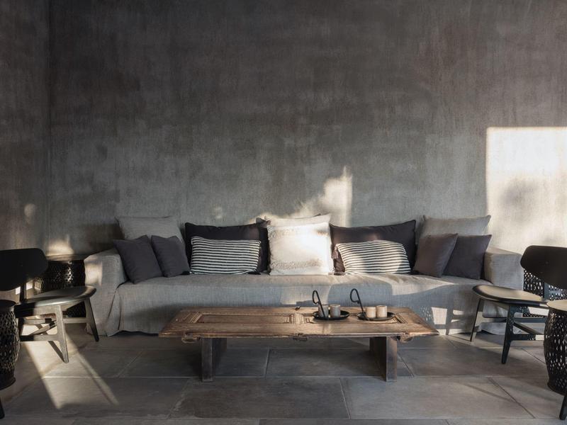 Salon confortable avec canapé gris, table en bois et plusieurs chaises noires au style moderne.