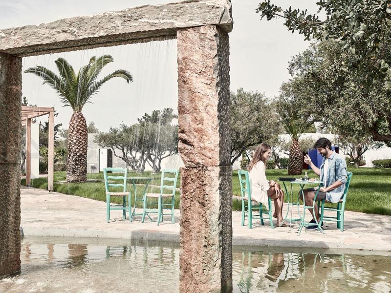 Portail en pierre avec espace de détente extérieur et personnes dans un jardin d'hôtel.