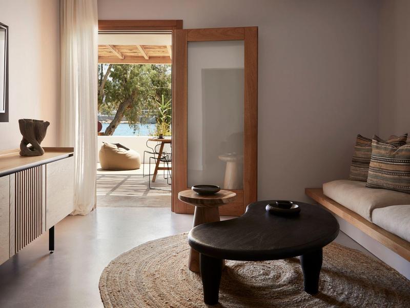 Salon élégant avec canapé, table basse ronde, tapis et accès à une terrasse extérieure.