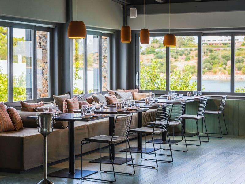 Espace lounge d'hôtel confortable avec grandes fenêtres et sièges modernes.