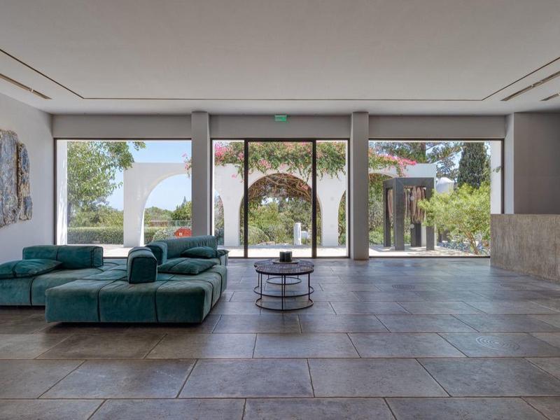 Hall d'hôtel moderne avec grandes fenêtres, canapé vert et œuvres d'art aux murs.