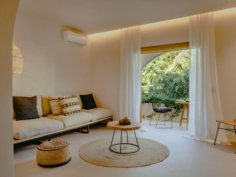 Salon lumineux avec canapé confortable, tapis rond et accès à un jardin