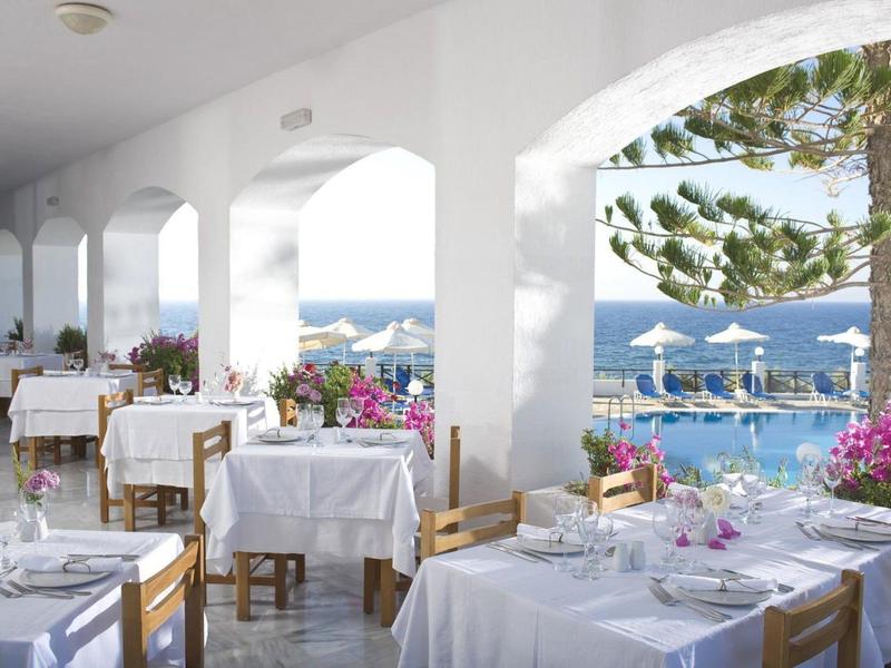 Ristorante aperto con tavoli bianchi con vista sul mare e ombrelloni