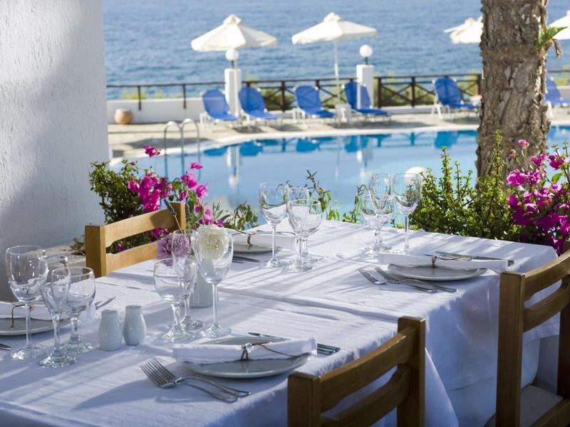 Tavolo apparecchiato sulla terrazza con vista sulla piscina e sul mare sullo sfondo.