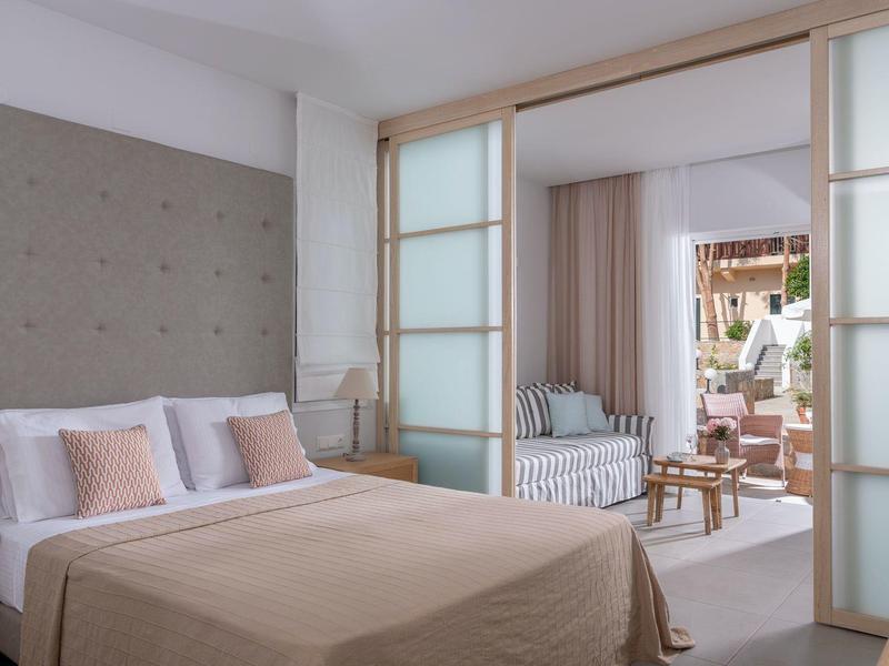 Camera d'hotel moderna con letto matrimoniale e area salotto adiacente con divano letto.