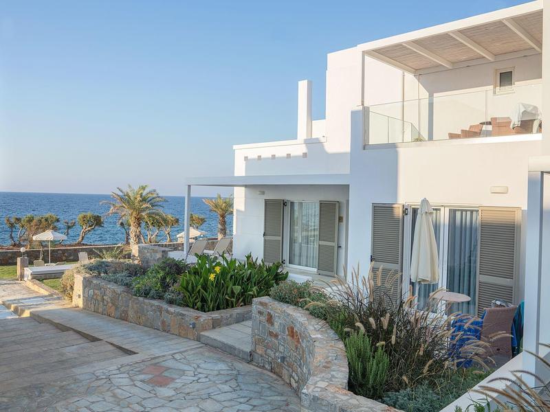 Edificio moderno bianco con terrazza e vista sul mare sotto un cielo limpido.