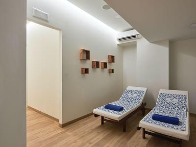Modern relaxation room with two loungers, blue towels, and wooden wall shelves.