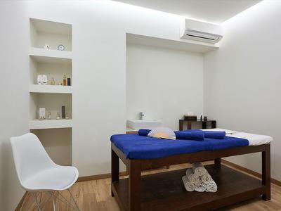 Bright spa treatment room with blue-covered table, white towels, and modern decor.