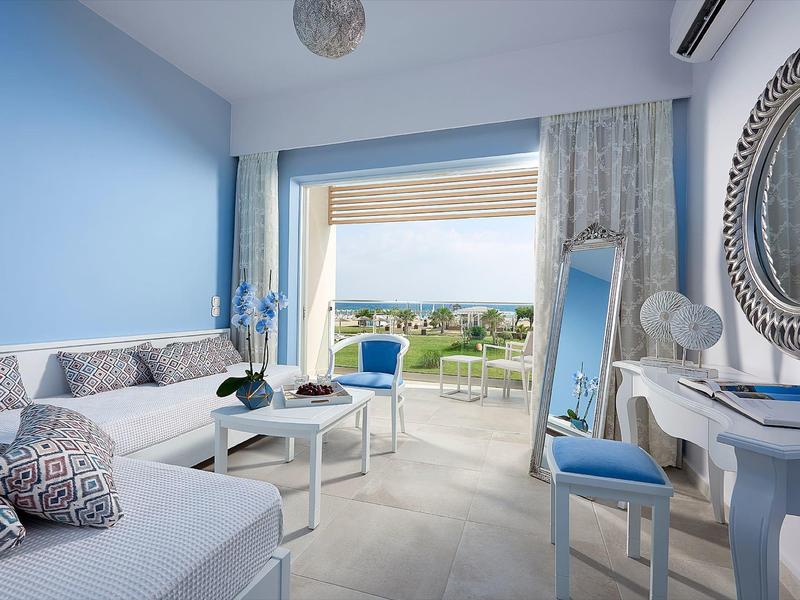 Bright hotel room with blue and white decor and view of a terrace with garden.