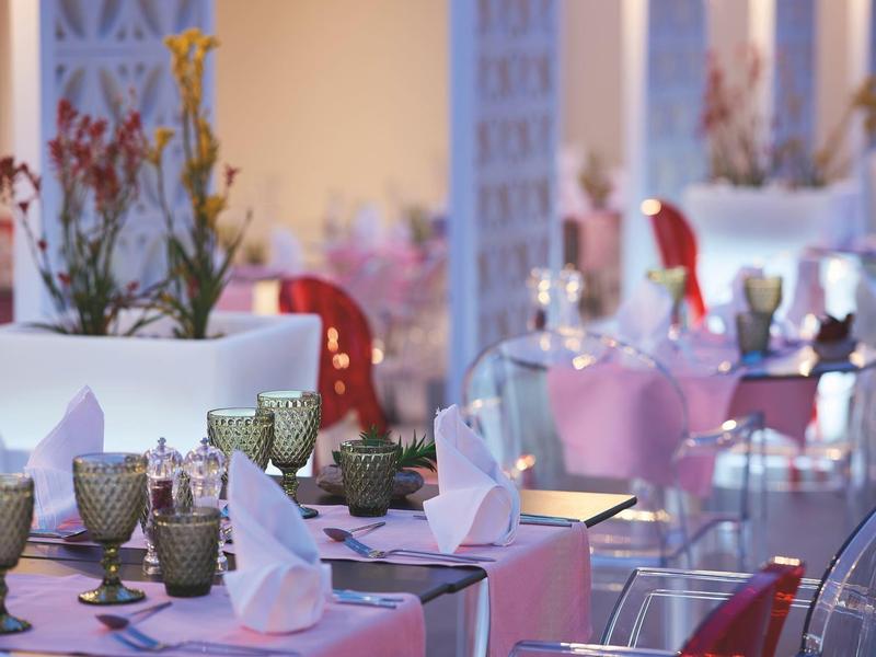 Elegant restaurant with white tablecloths, green glasses, and floral decorations.