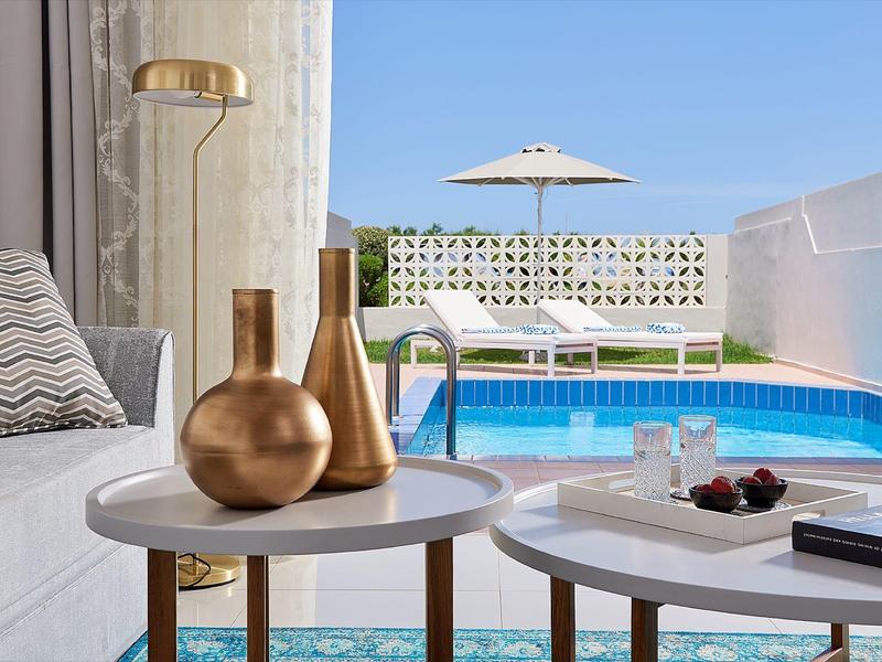 Elegant terrace with pool, white loungers, and decorative copper vases on tables.