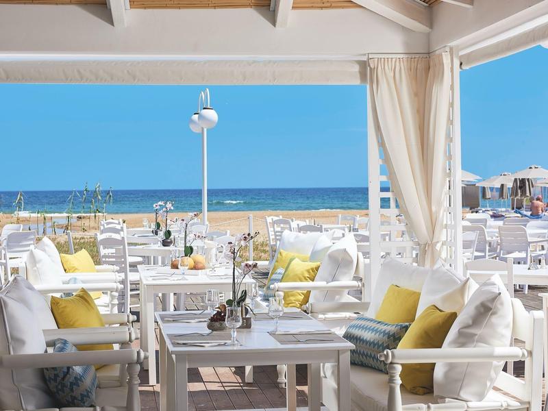 Bright terrace with white furniture and sea view under clear weather.