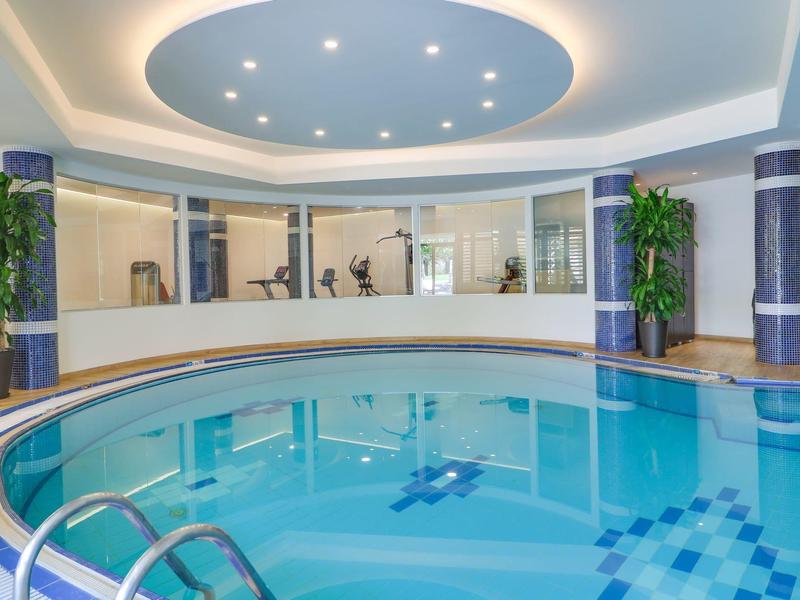 Indoor round pool with blue lighting and plants in a modern hotel