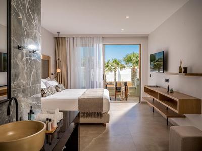 Habitación de hotel moderna con cama grande, balcón y vista a palmeras.