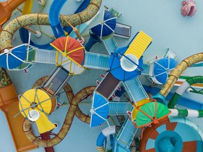 Bunte Wasserrutschen mit Sonnenschirmen und Sitzplätzen im Wasserpark eines Hotels.