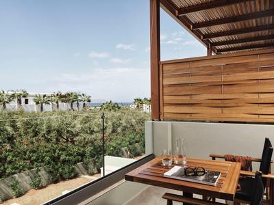 Terraza de madera con mesa y sillas con vistas al jardín y paisaje lejano.