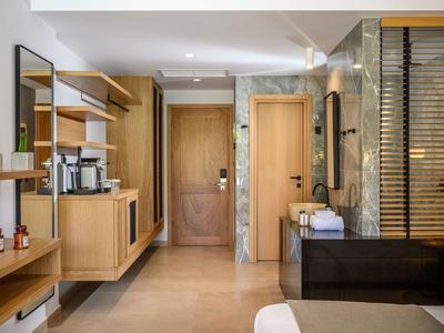 Nowoczesny hotelowy korytarz z drewnianymi meblami, dużym lustrem i szklaną umywalką.