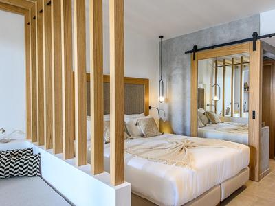 Nowoczesny pokój hotelowy z łóżkiem podwójnym, drewnianymi elementami i drzwiami przesuwanymi z drewna.