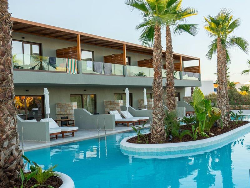 Piscina moderna del hotel con palmeras y tumbonas en un entorno tropical.