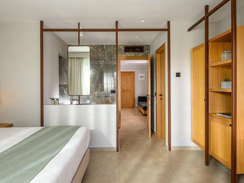 Habitación de hotel moderna con cama doble, muebles de madera y área de baño abierta.