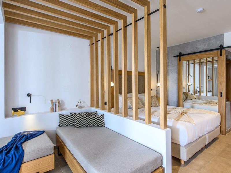 Habitación de hotel moderna con decoración en madera, camas cómodas y área de descanso.